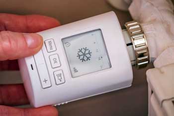 Hand touching a radiator thermostat